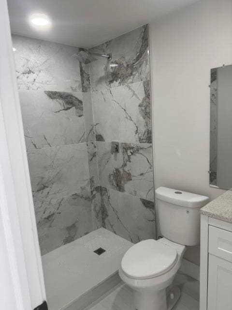 full bath featuring a marble finish shower, toilet, marble finish floor, and vanity