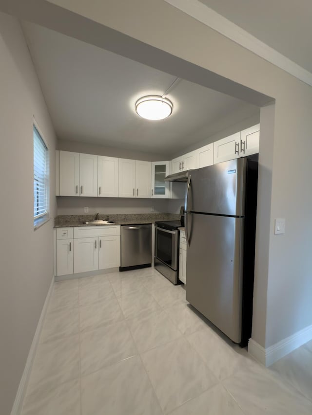 kitchen with dark countertops, glass insert cabinets, baseboards, stainless steel appliances, and white cabinetry