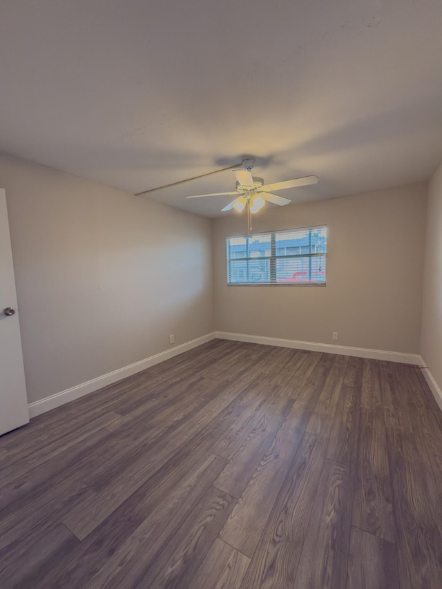 spare room with a ceiling fan, baseboards, and dark wood-style flooring