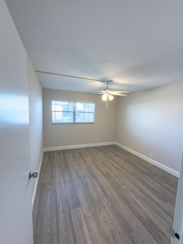 empty room featuring ceiling fan, baseboards, and wood finished floors