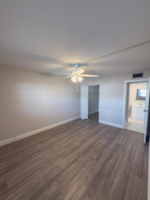 empty room featuring dark wood-style floors, visible vents, ceiling fan, and baseboards