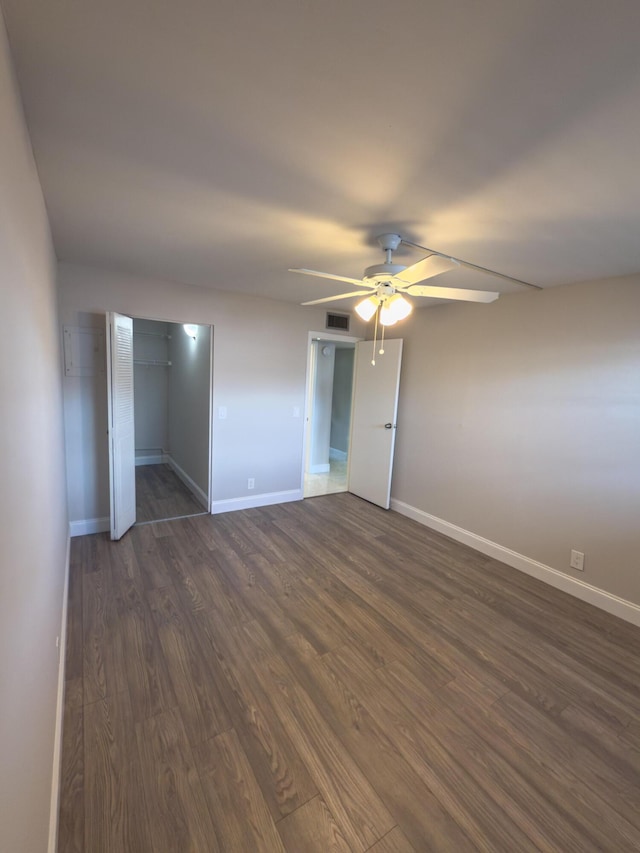 unfurnished bedroom with dark wood-style floors, visible vents, a ceiling fan, and baseboards