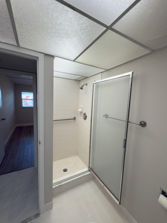 full bath with tile patterned flooring, baseboards, a stall shower, and a paneled ceiling