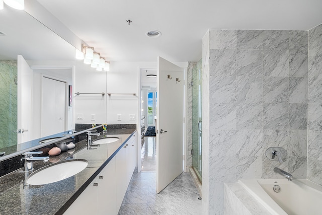 ensuite bathroom with double vanity, a stall shower, a tub, and a sink