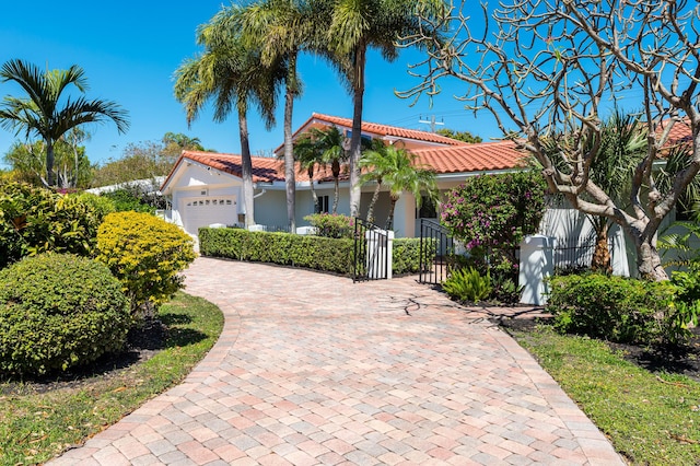 2601 NE 37th St, Fort Lauderdale, FL 33306 - mediterranean / spanish house with an attached garage, a tile roof, decorative driveway, and stucco siding
