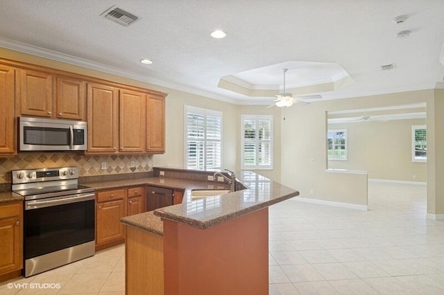 kitchen with visible vents, a tray ceiling, a sink, stainless steel appliances, and crown molding