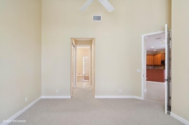 unfurnished bedroom with visible vents, light colored carpet, baseboards, and a towering ceiling