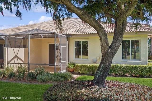 back of house with a lanai, stucco siding, and a tile roof