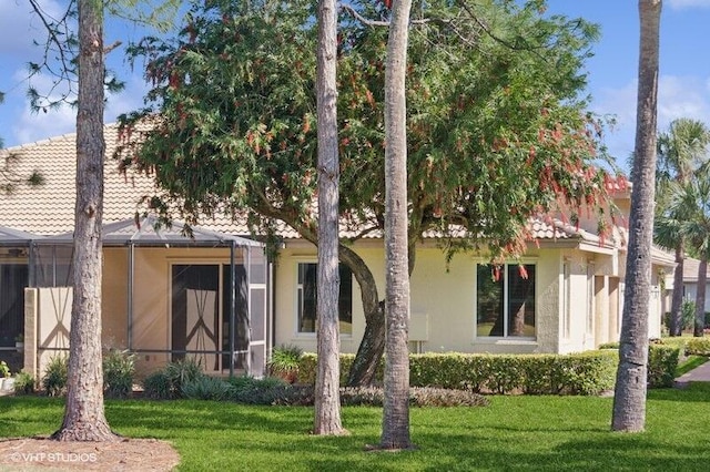 view of front of property featuring stucco siding, a front lawn, and a tile roof