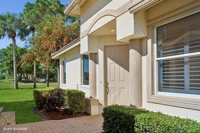 property entrance featuring stucco siding and a yard