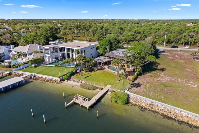 dock area with a water view, a lanai, a yard, a patio area, and an outdoor pool