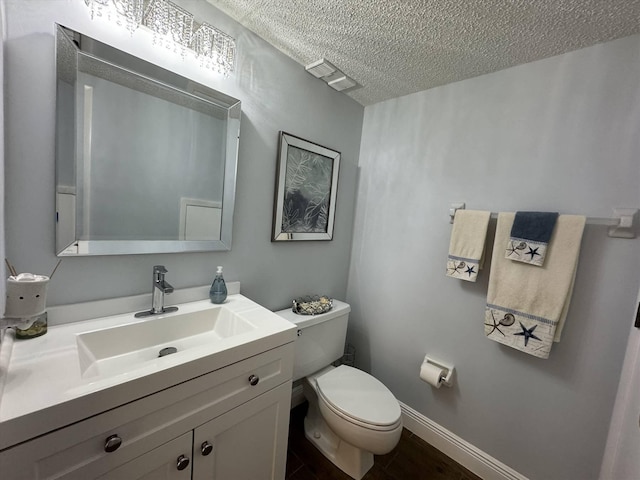 bathroom with visible vents, toilet, a textured ceiling, baseboards, and vanity