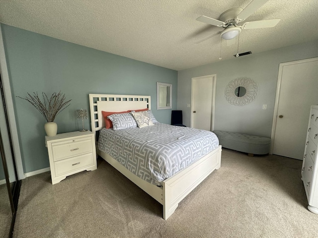 carpeted bedroom with visible vents, a textured ceiling, and ceiling fan