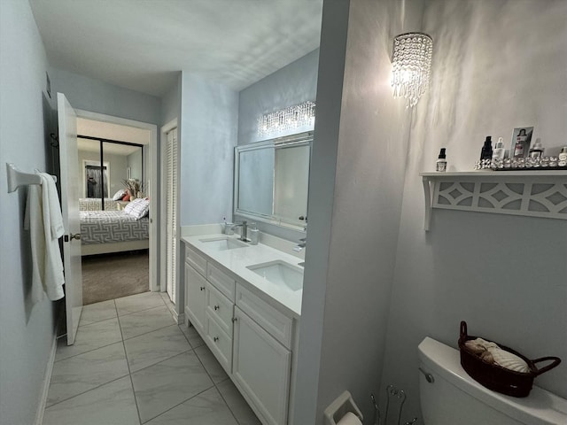 ensuite bathroom featuring toilet, connected bathroom, marble finish floor, and a sink