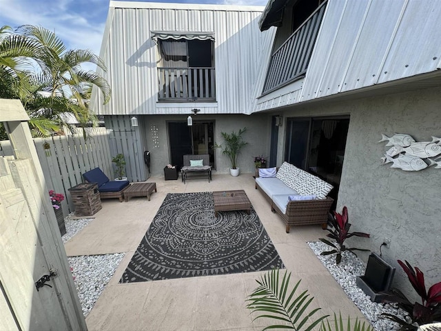 view of patio with outdoor lounge area, a balcony, and fence