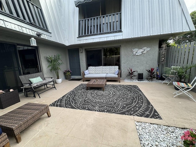 view of patio with an outdoor living space, a balcony, and fence