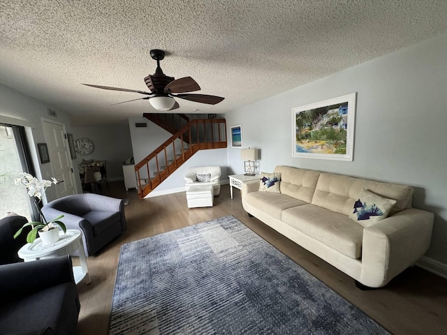 living room with a textured ceiling, stairs, ceiling fan, and wood finished floors