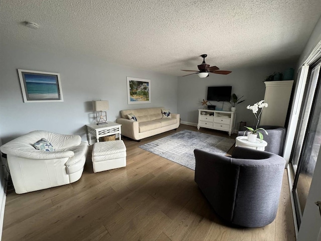 living area with a ceiling fan, wood finished floors, and a textured ceiling