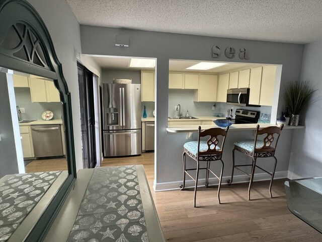 kitchen featuring appliances with stainless steel finishes, light countertops, light wood-style floors, and a sink