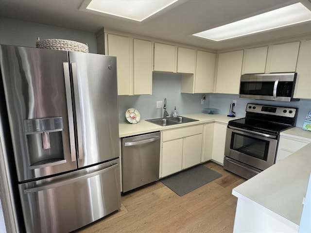 kitchen with a sink, light countertops, light wood-style floors, and stainless steel appliances