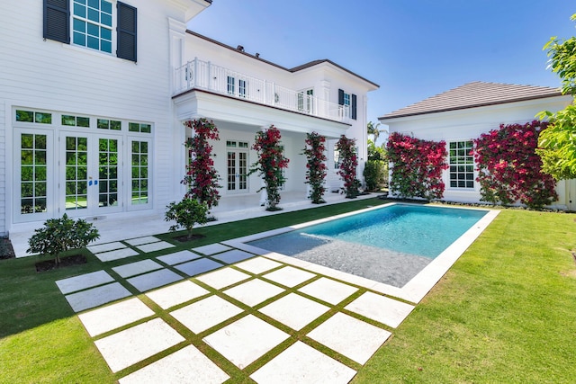 pool with french doors, a patio, and a yard