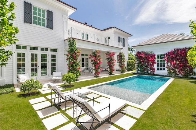 205 Gray St, West Palm Beach, FL 33405 - back of property with french doors, a patio area, a balcony, a lawn, and an outdoor pool