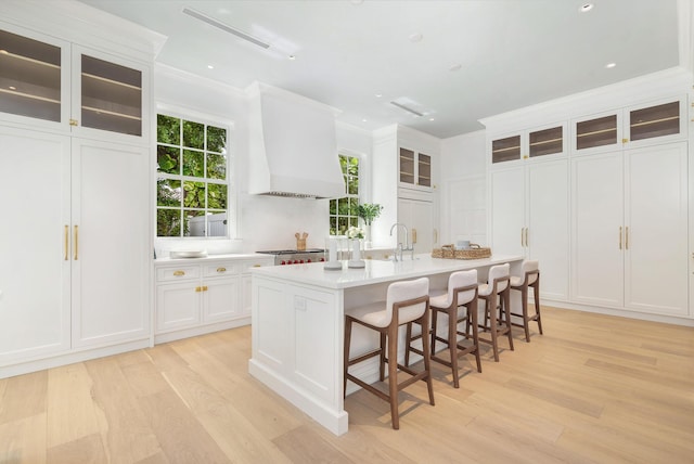 205 Gray St, West Palm Beach, FL 33405 - kitchen featuring custom exhaust hood, light wood finished floors, ornamental molding, a kitchen island with sink, and light countertops