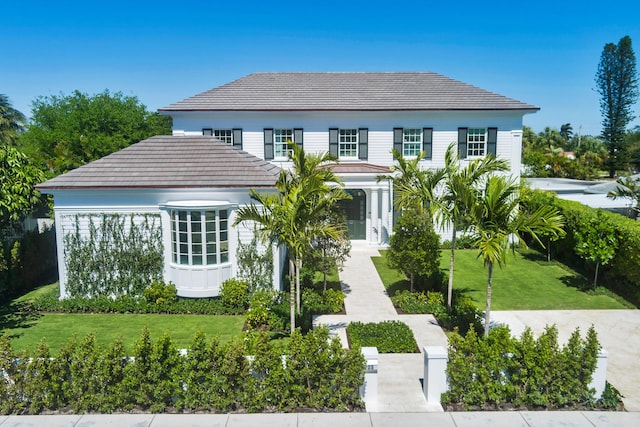 view of front of property featuring a front lawn and a tiled roof