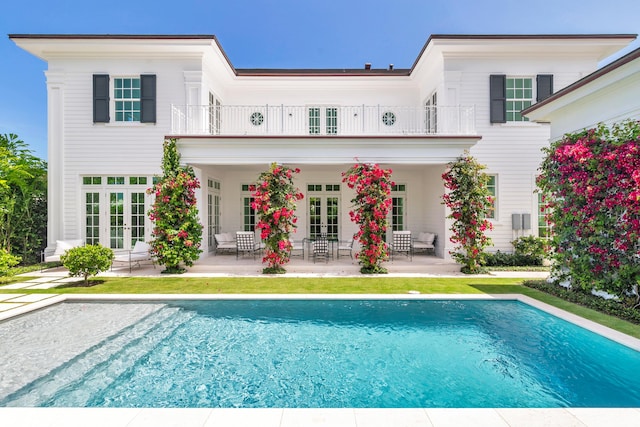 205 Gray St, West Palm Beach, FL 33405 - back of house featuring french doors, a balcony, a patio area, and an outdoor pool