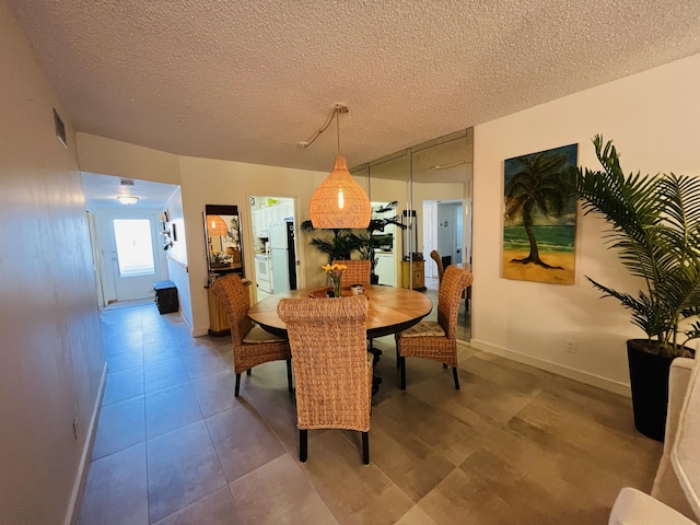 dining space featuring tile patterned flooring, visible vents, a textured ceiling, and baseboards