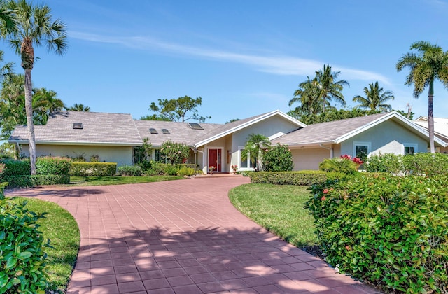 single story home featuring a front lawn, decorative driveway, and stucco siding