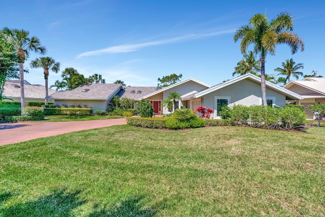 single story home featuring a front yard, decorative driveway, and stucco siding