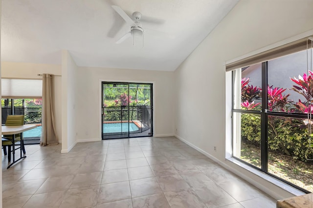 unfurnished room with a healthy amount of sunlight, baseboards, ceiling fan, and vaulted ceiling