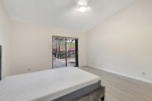 bedroom with a ceiling fan, wood finished floors, baseboards, access to exterior, and vaulted ceiling