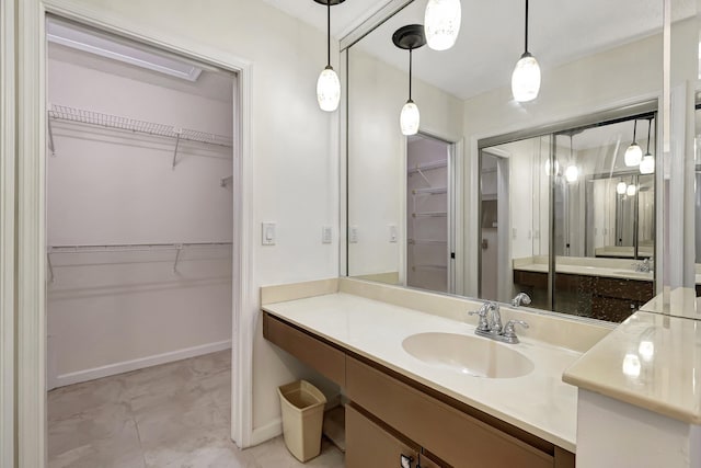 full bath featuring vanity, a walk in closet, and baseboards