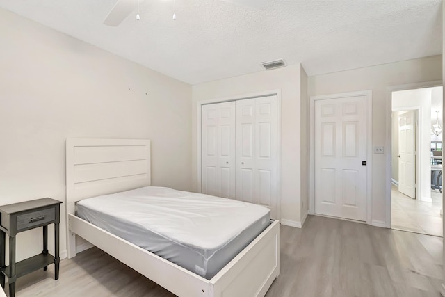 bedroom featuring visible vents, light wood-style floors, a closet, and a textured ceiling