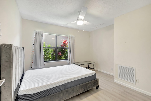 bedroom featuring visible vents, baseboards, a textured ceiling, and light wood finished floors