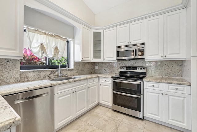 kitchen with backsplash, glass insert cabinets, white cabinets, stainless steel appliances, and a sink