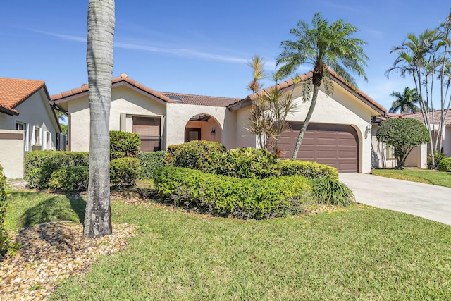 mediterranean / spanish home featuring a front yard, driveway, stucco siding, a garage, and a tiled roof