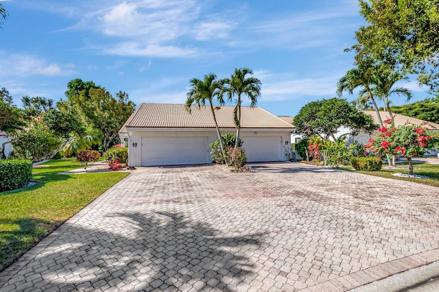 ranch-style home with a tiled roof, a front lawn, decorative driveway, and a garage