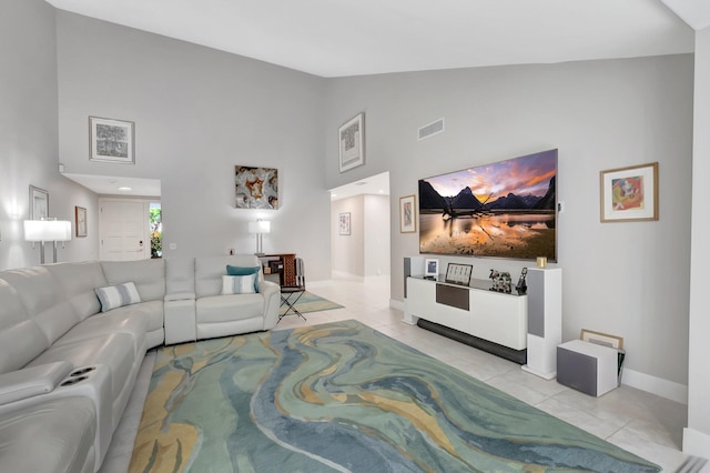 living area with light tile patterned floors, baseboards, visible vents, and high vaulted ceiling