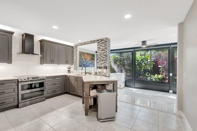 kitchen with gray cabinetry, a sink, double oven range, wall chimney exhaust hood, and light countertops