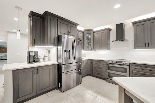 kitchen with tasteful backsplash, glass insert cabinets, wall chimney range hood, pendant lighting, and stainless steel appliances