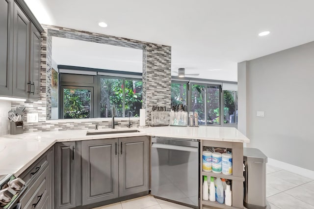 kitchen featuring light tile patterned floors, a healthy amount of sunlight, a sink, stainless steel dishwasher, and tasteful backsplash