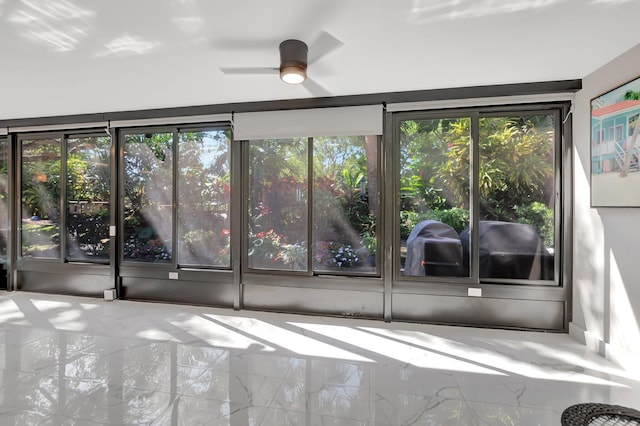 spare room featuring a wealth of natural light, marble finish floor, and ceiling fan