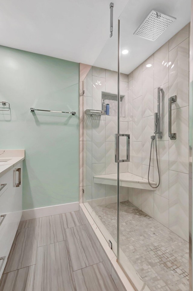 full bathroom featuring baseboards, a stall shower, and vanity