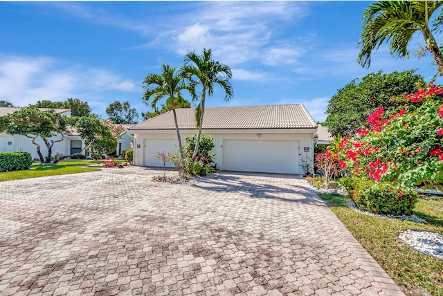 view of front facade featuring a tiled roof, decorative driveway, and an attached garage