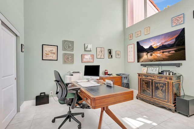 home office with baseboards, a high ceiling, and tile patterned flooring