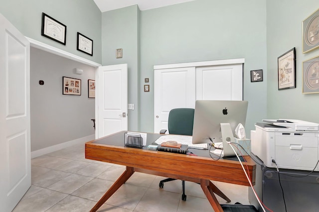 home office with light tile patterned floors, baseboards, and a towering ceiling