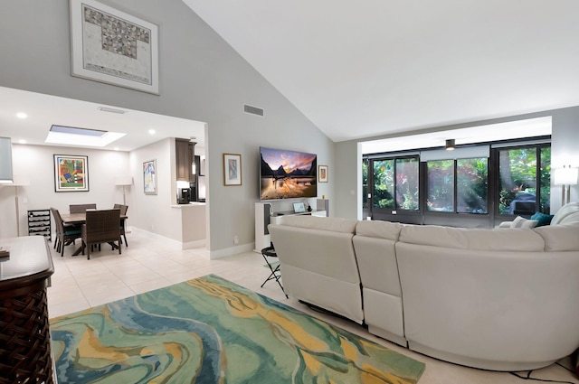 living room featuring visible vents, high vaulted ceiling, a skylight, light tile patterned flooring, and baseboards